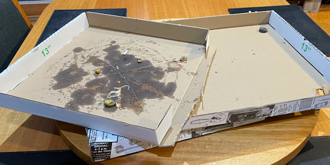 A pizza box separated into two halves: one clean and the other oily and food-stained