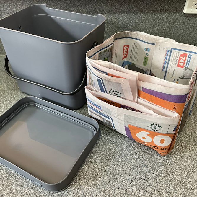 Newspaper folded into a bucket shape to serve as a lining for the compost caddy