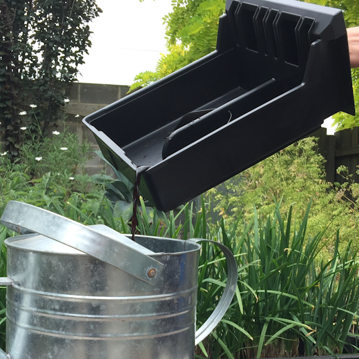 Harvested compost juice being poured into a watering can.